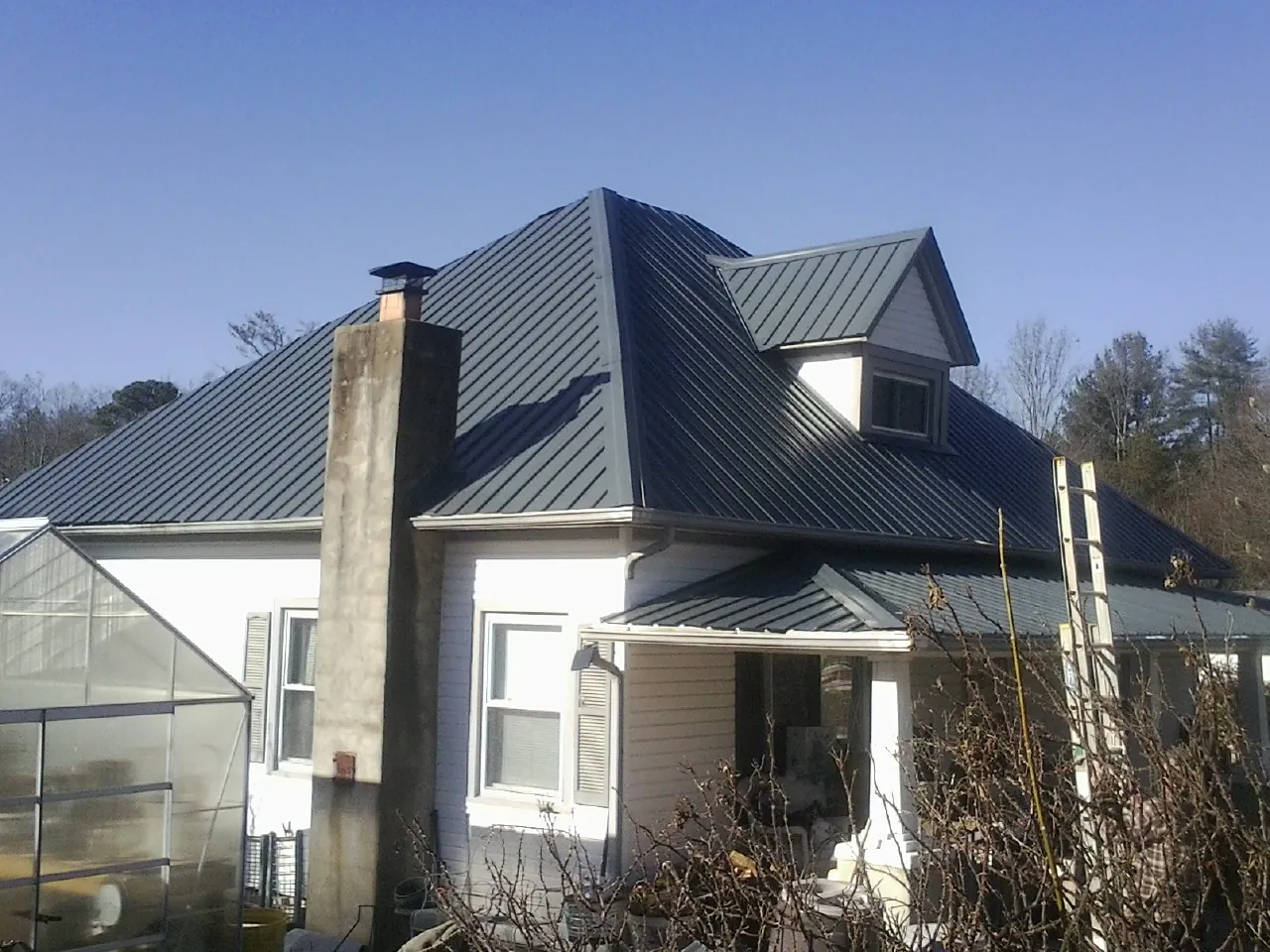 Dark blue standing seam metal roof on a white farmhouse with dormer — Slate & Tile Roof Repair by Roofing Brothers in Armona