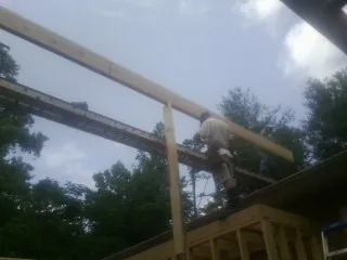 Carpenter setting a ridge beam over a new addition frame — Ice Dam Removal by Roofing Brothers in Armona