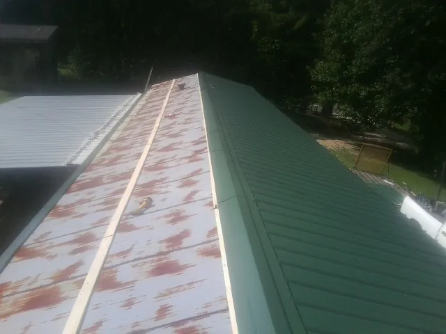 Old rusted panels beside newly installed green metal roofing — Wind Damage Roof Repair by Roofing Brothers in Armona