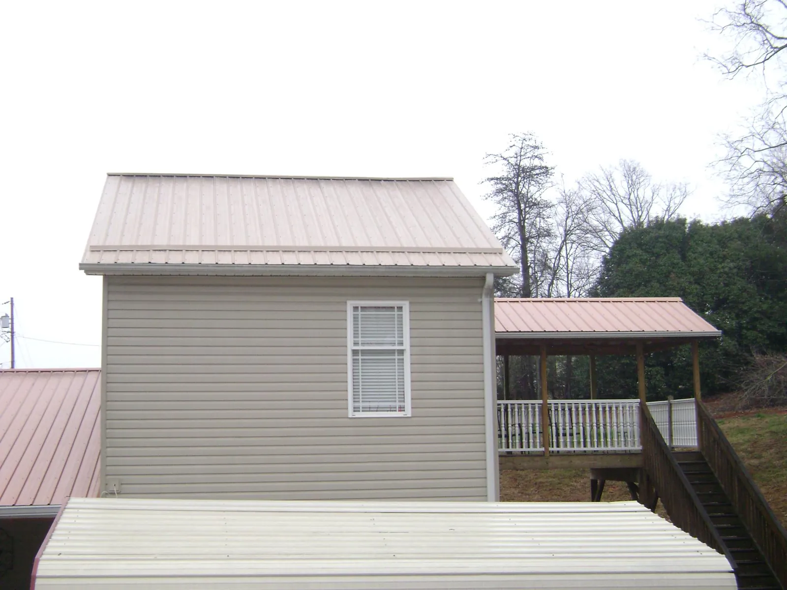 Tan metal roofs on a two story addition and attached porch, from a Roof Replacement job in Armona