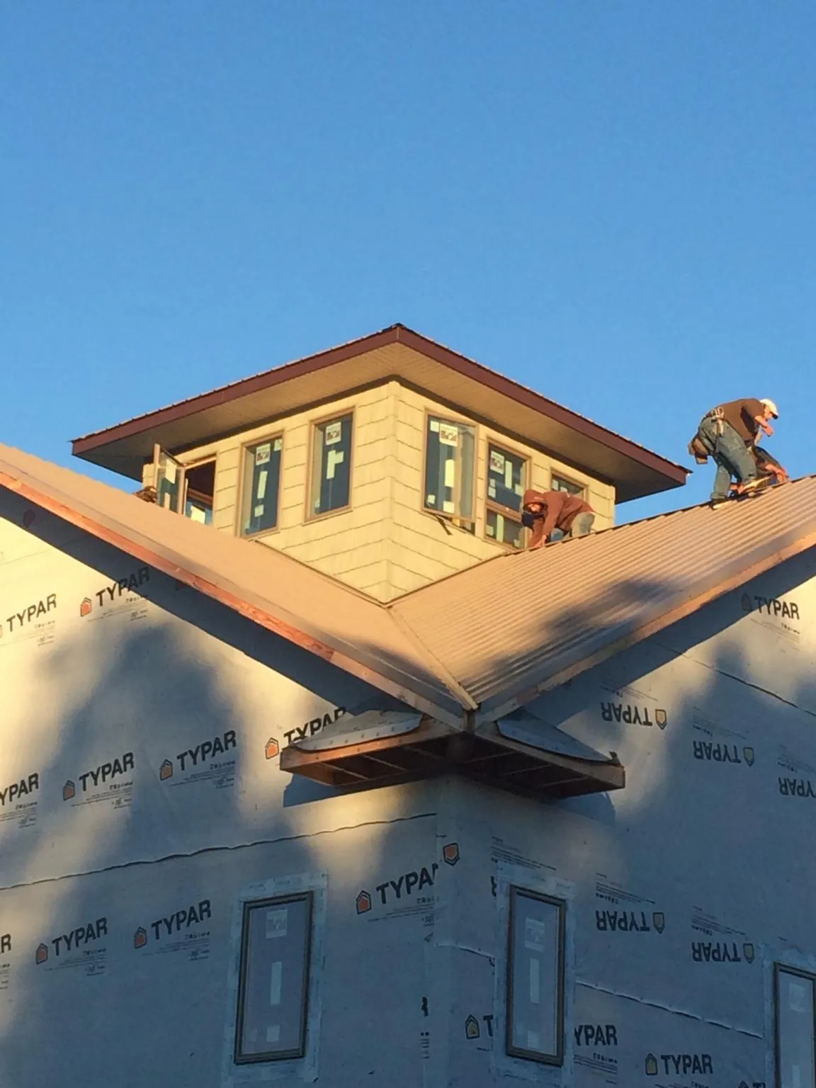 Roofers working around a rooftop cupola on a new metal roof at sunset — Roof Waterproofing in Armona by Roofing Brothers